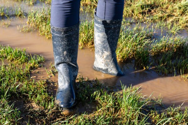 A woman viewed from the knees down, wearing wellies on a muddy path in Sussex