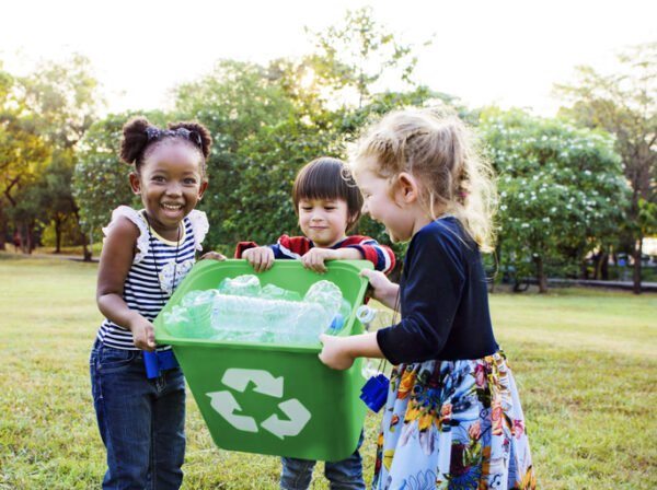 Group of smiling kids collecting plastic bottles to recycle